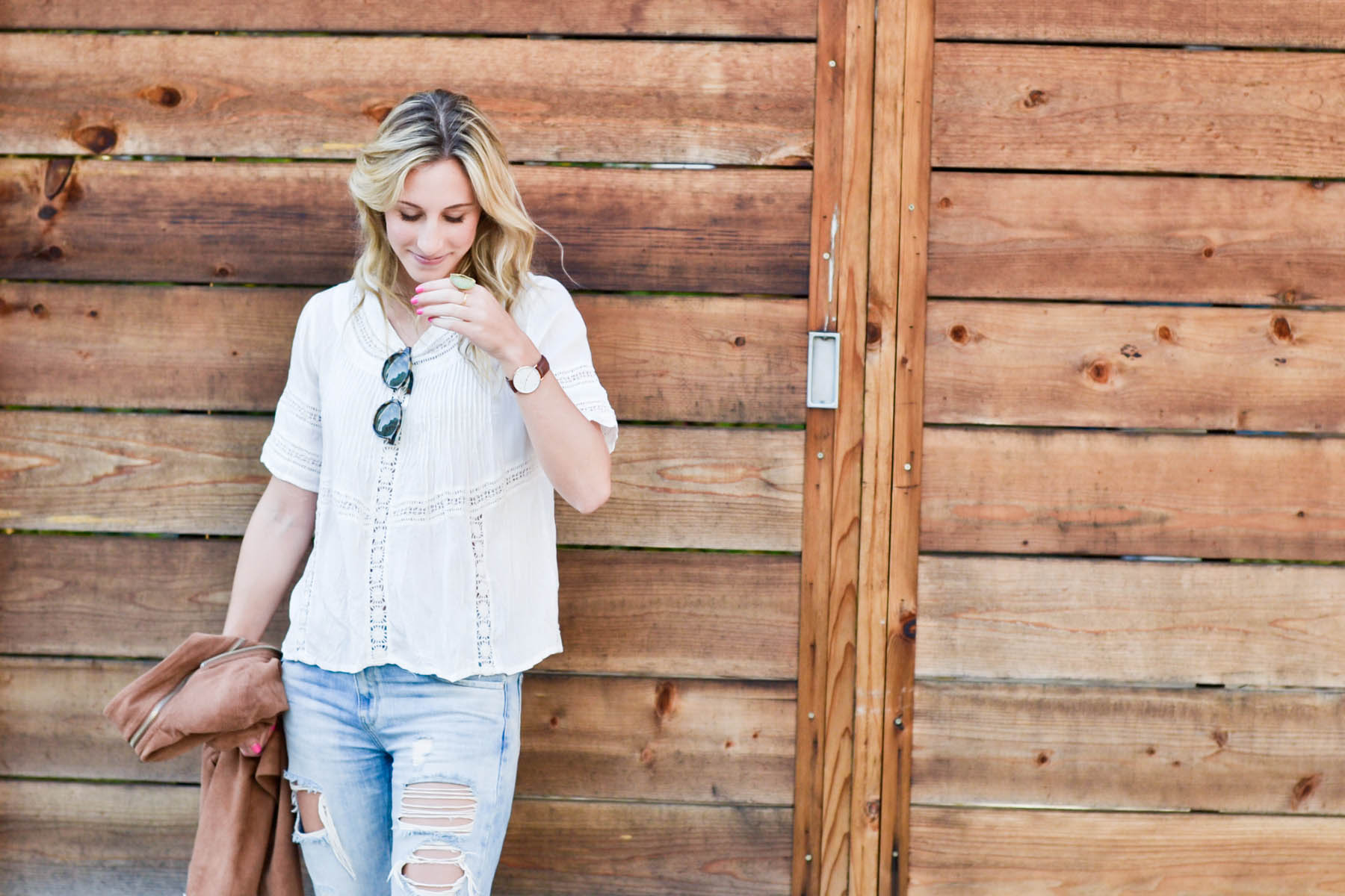 Amanda Holstein in revolve clothing white lace top, madewell sunglasses, brown suede moto jacket, ripped boyfriend jeans, distressed denim