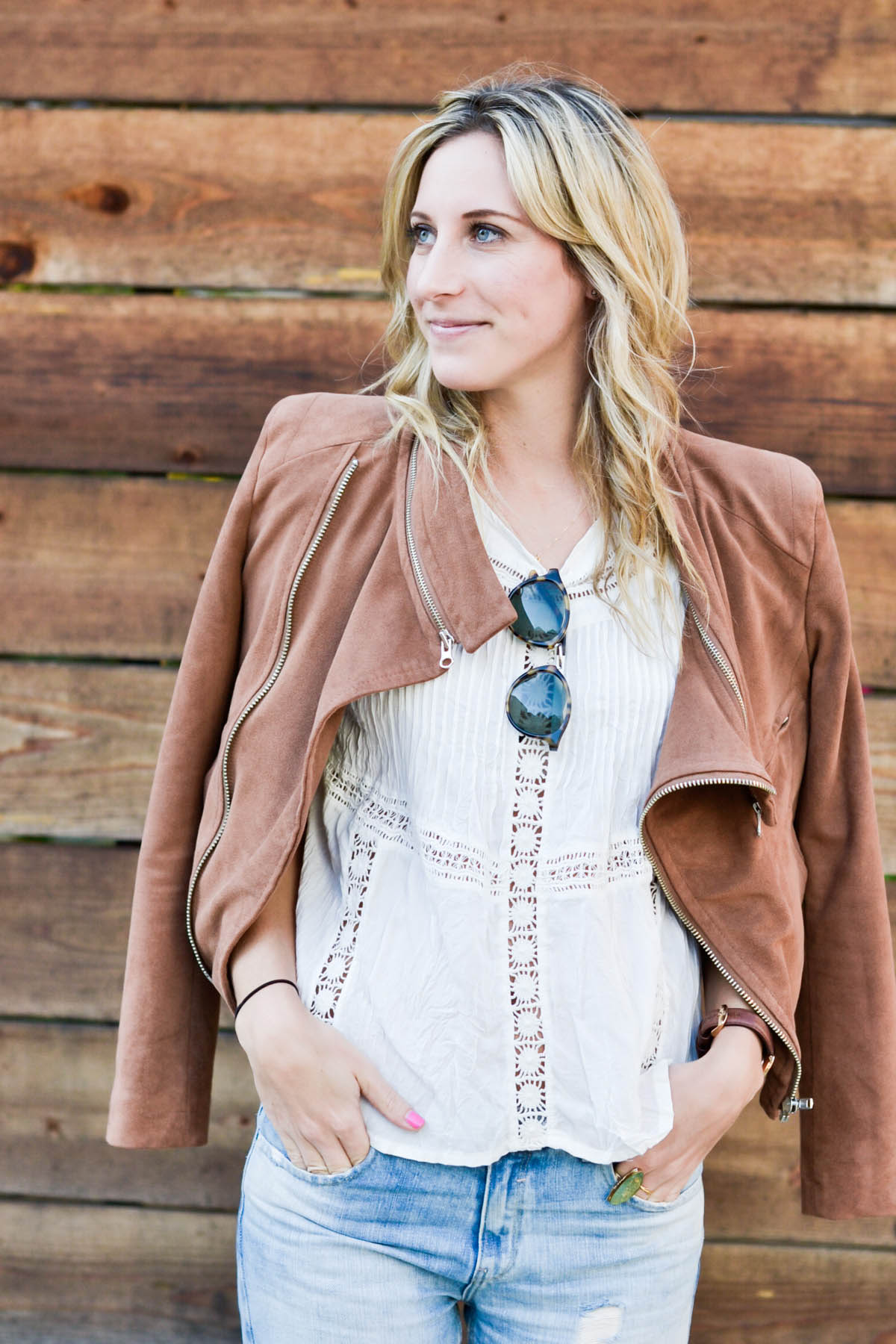Amanda Holstein in revolve clothing white lace top, madewell sunglasses, brown suede moto jacket