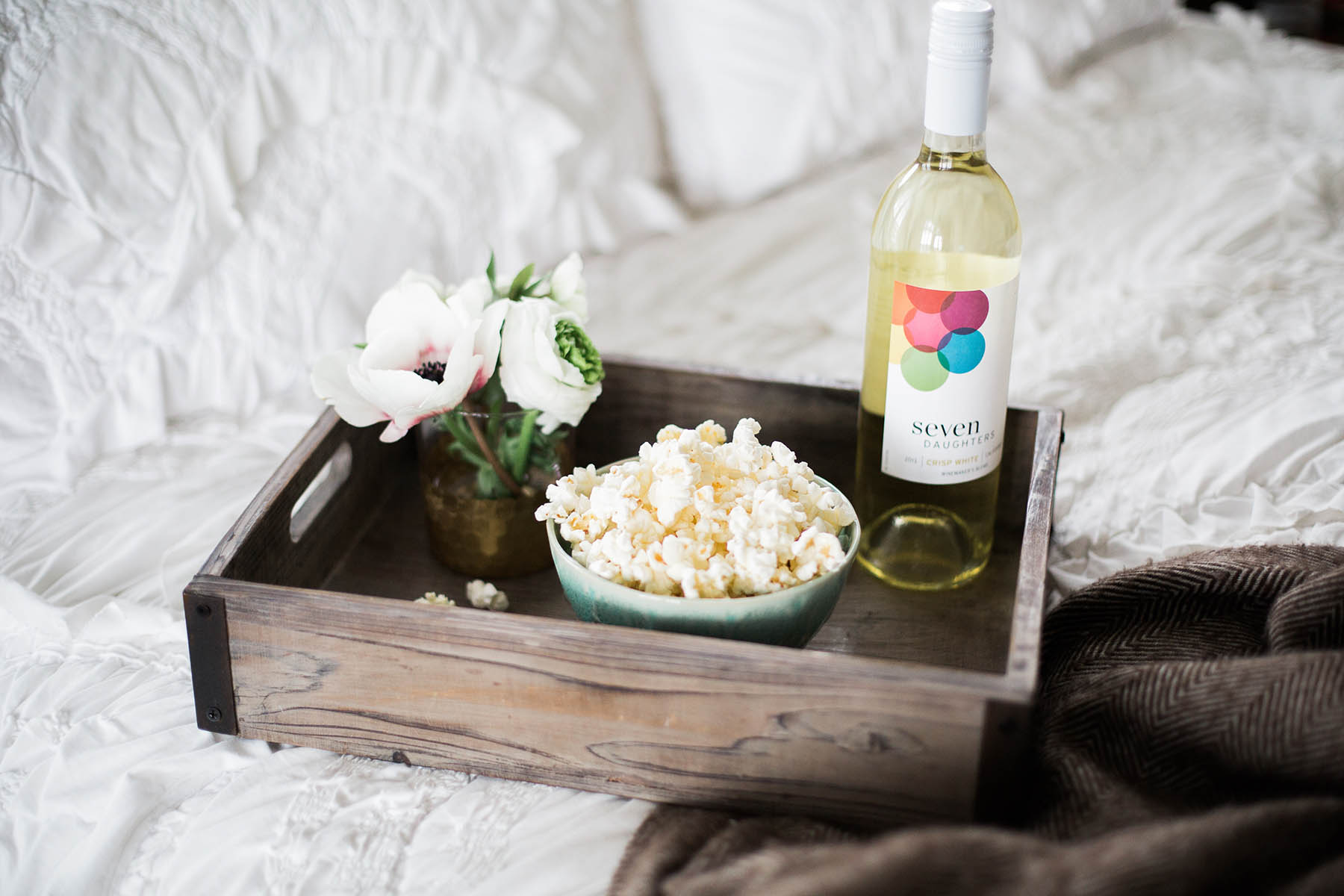 tray of popcorn and seven daughters wine on bed for movie night