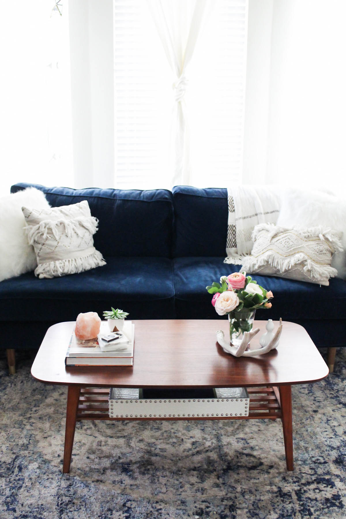 Urban Outfitters coffee table with navy couch in feminine living room