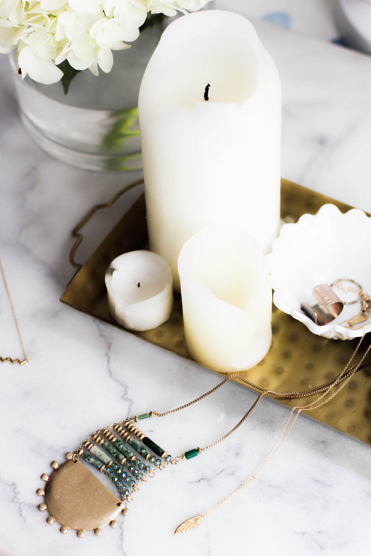 necklaces on vanity with candles and gold tray