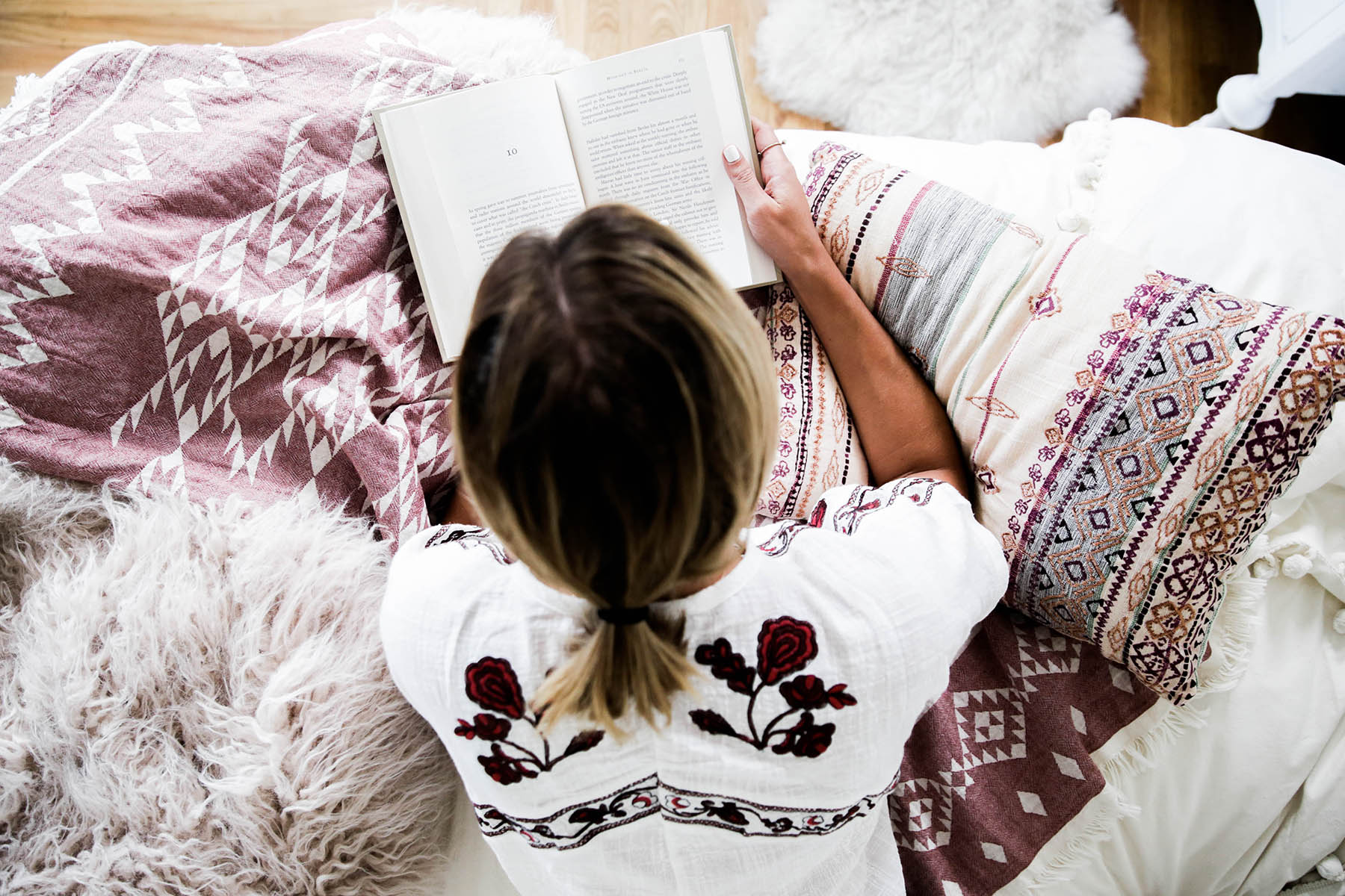 Amanda Holstein reading in bed with Urban Outfitters Urban Outfitters bedroom with Magical Thinking Pom-Fringe Duvet Cover and Agda Printed Yarn Pillow