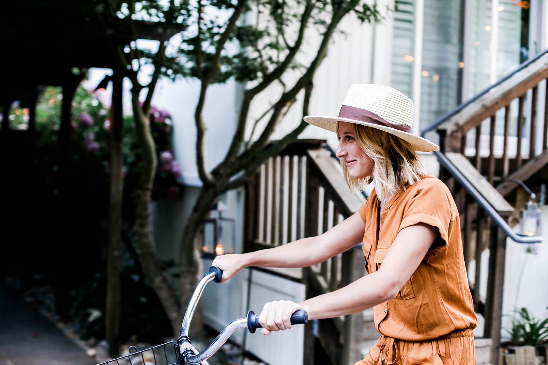 Amanda Holstein riding bikes in Old Navy romper and woven fedora hat