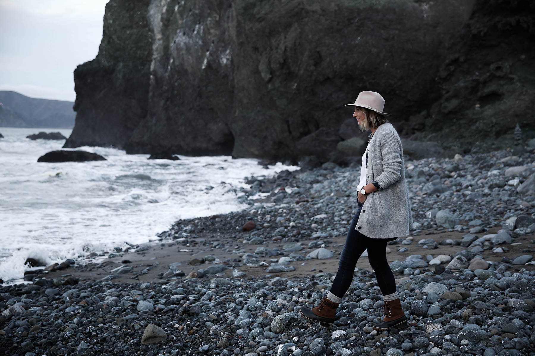 san francisco hikes on beach in sorel boots and grey cardigan