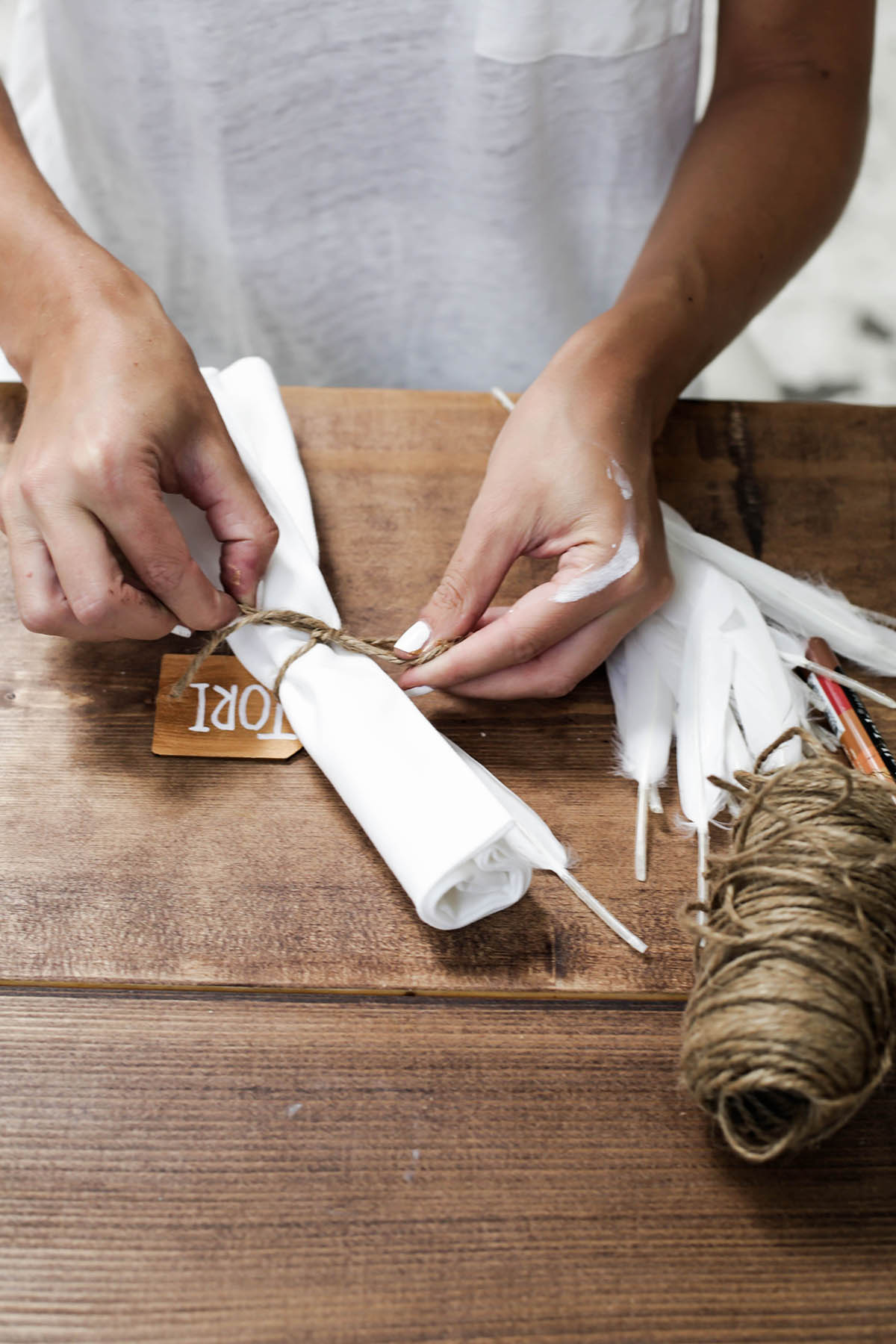 DIY name tag table setting with twine and feathers and white napkins