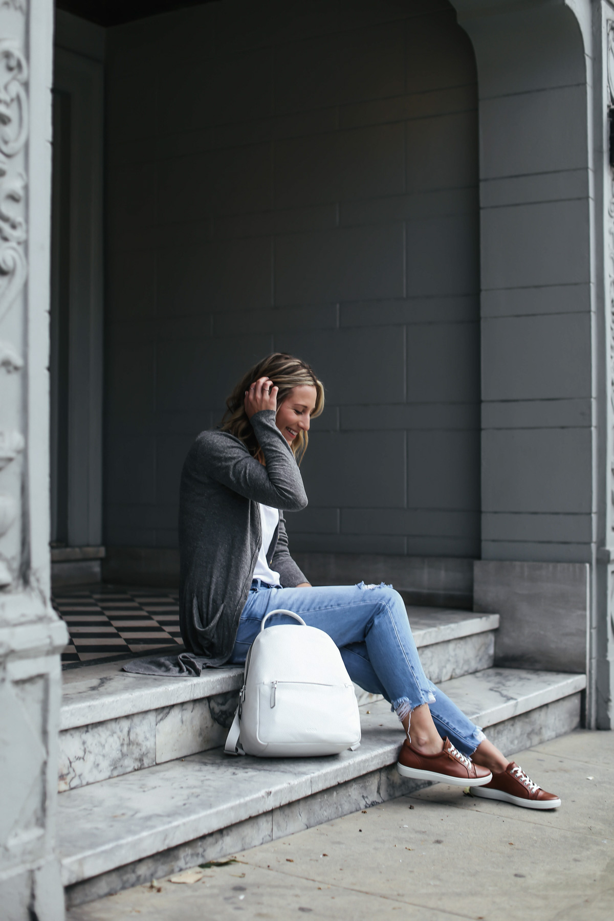 travel outfit with brown leather sneakers and white leather backpack