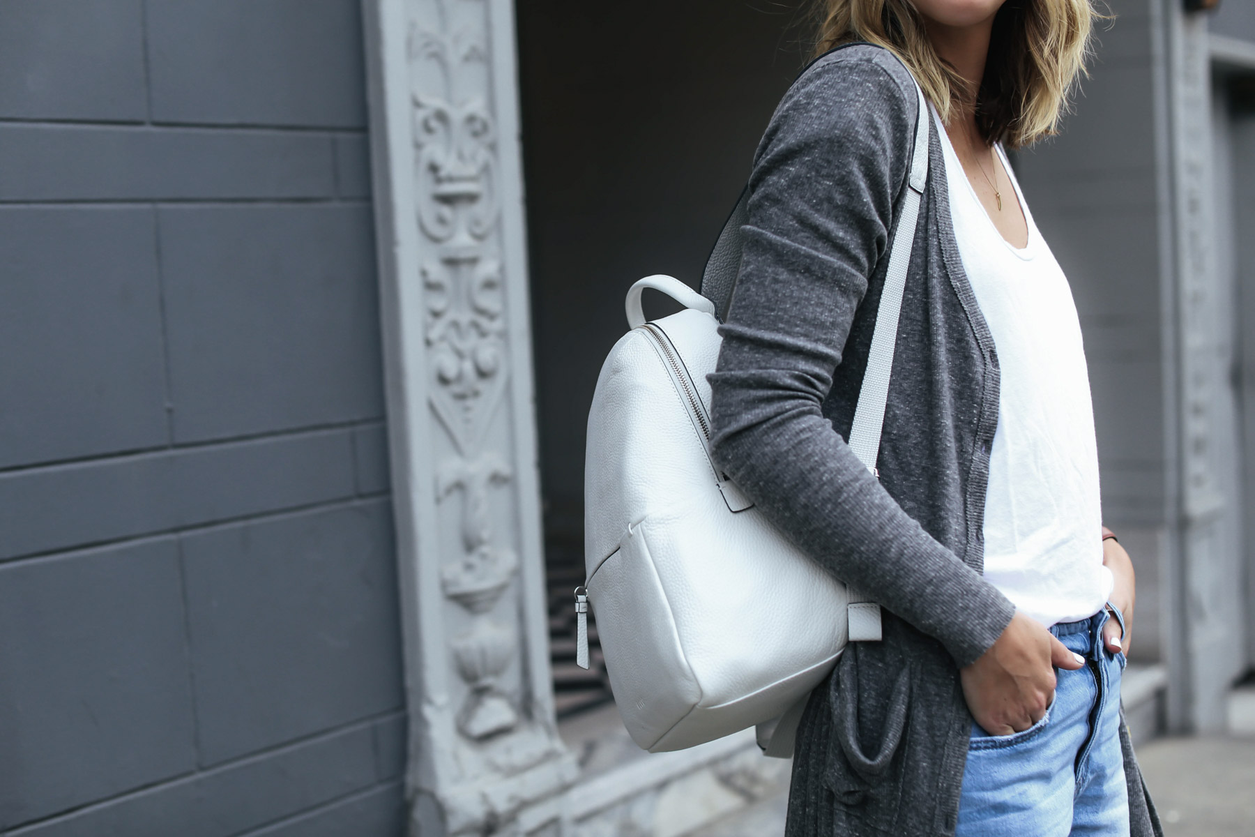 white leather backpack and gray cardigan travel outfit