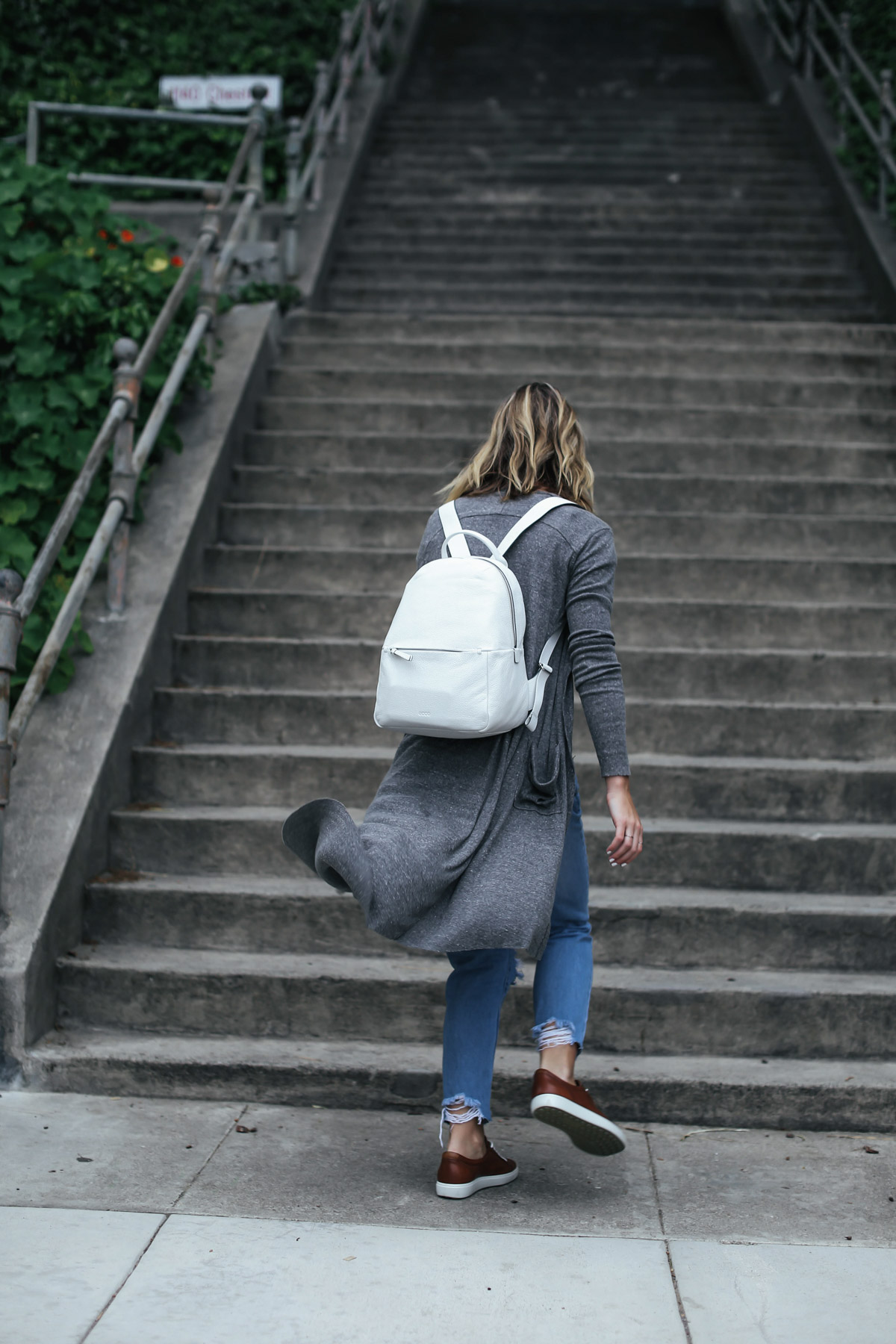 travel outfit white leather backpack and gray cardigan