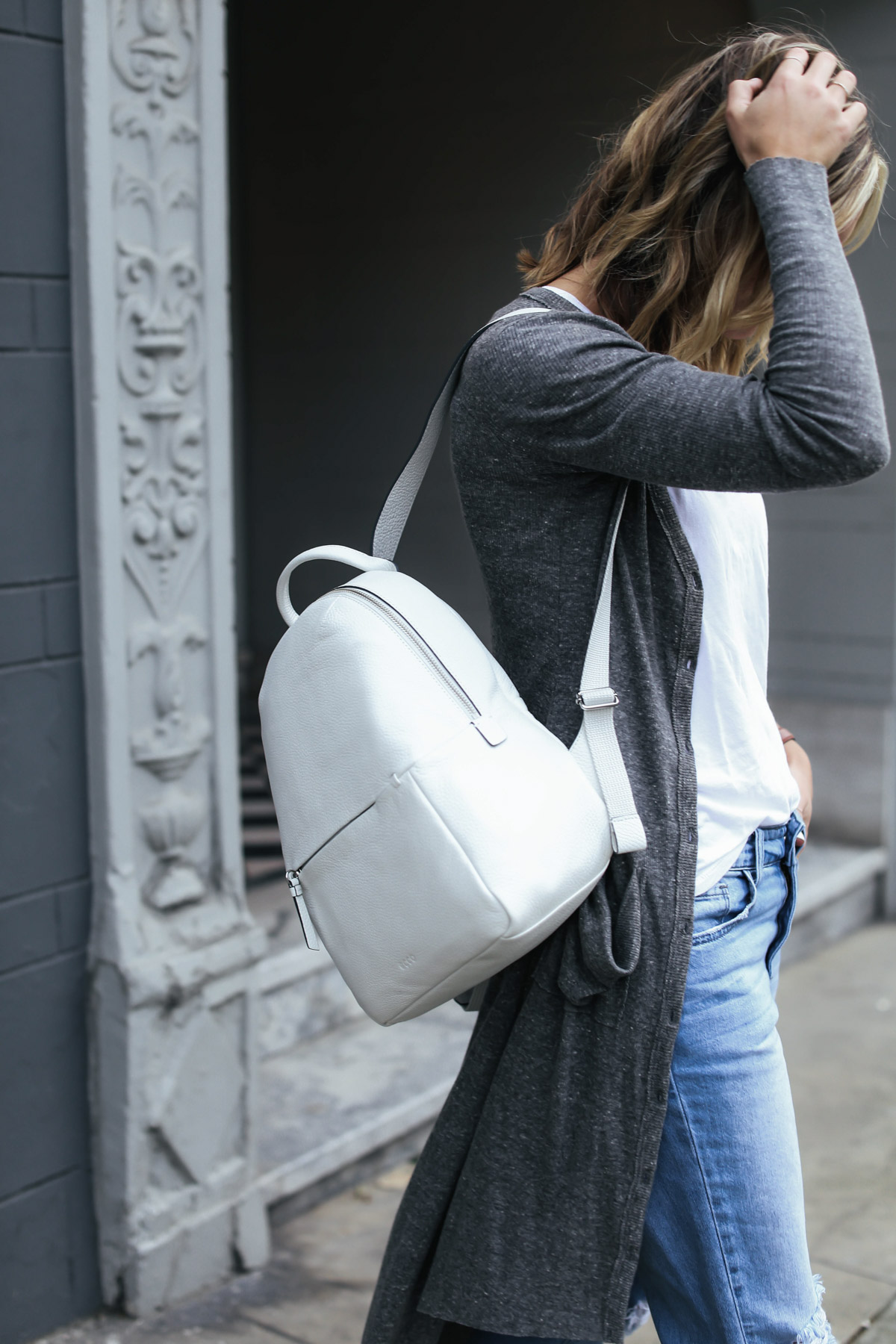 travel outfit white leather backpack and gray cardigan